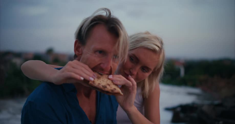 Woman feeding pizza into her boyfriends mouth in a romantic way