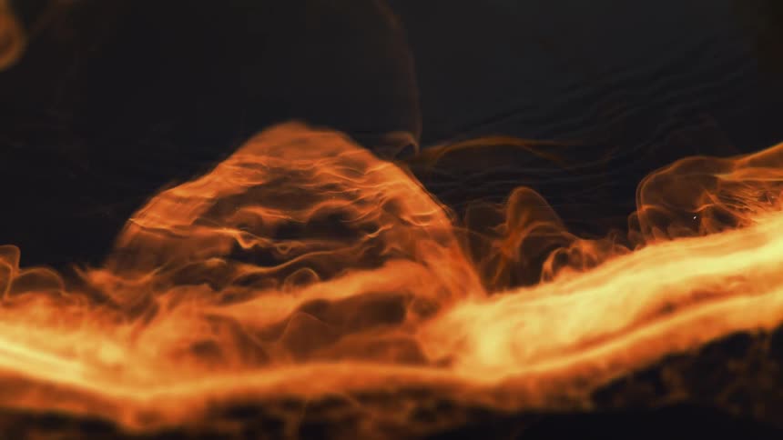 A yellow orange liquid bubbling and washing away against a dark background