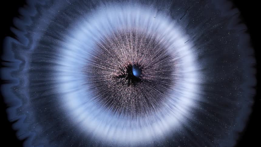 A circular explosion of blue particles on a black background