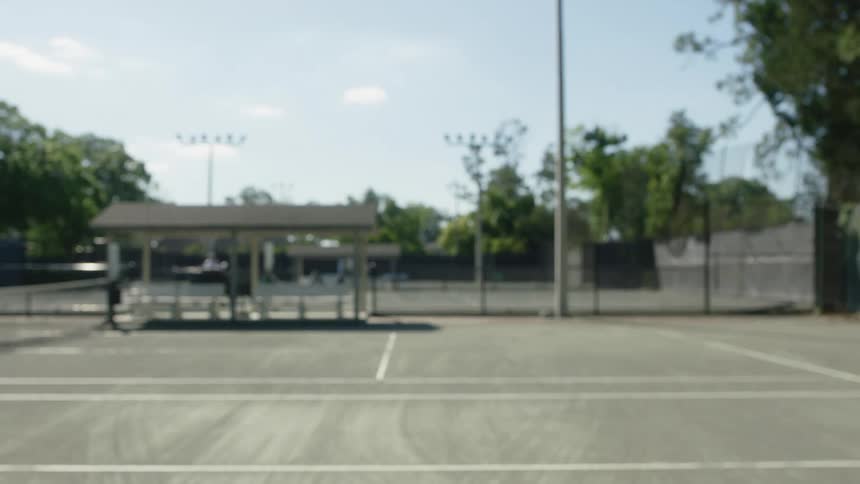 Hand holding a racket on a tennis court and hitting a green ball