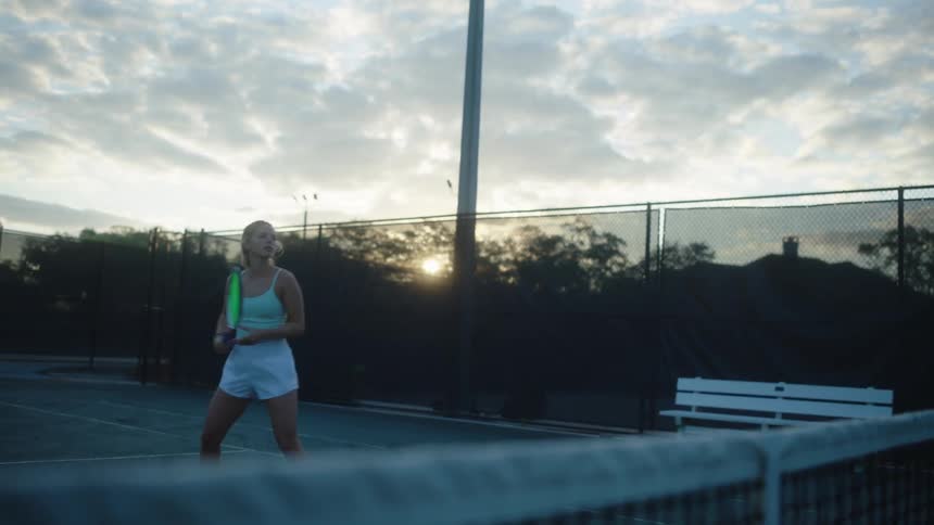 Tennis player performing a serve at sunset