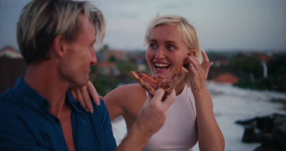 Man and woman eating pizza and then kissing
