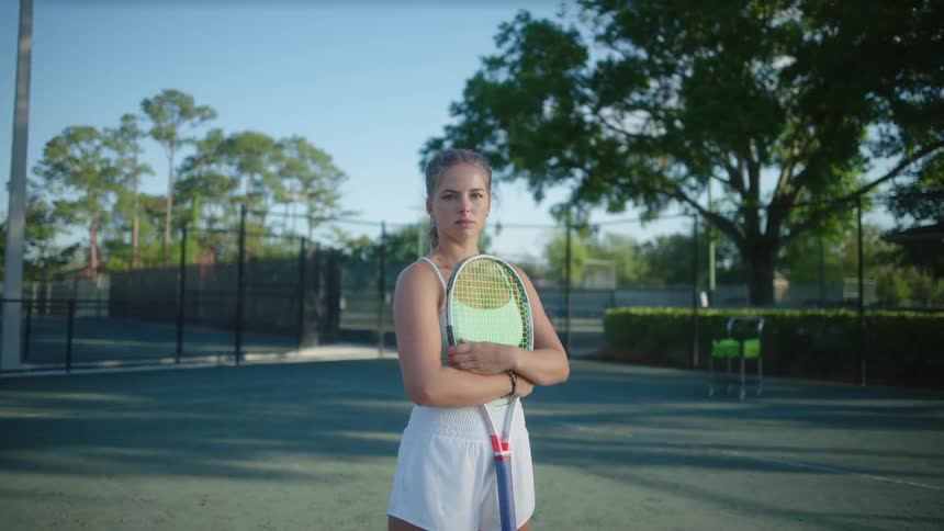 A tennis player stands on a court holding a racket