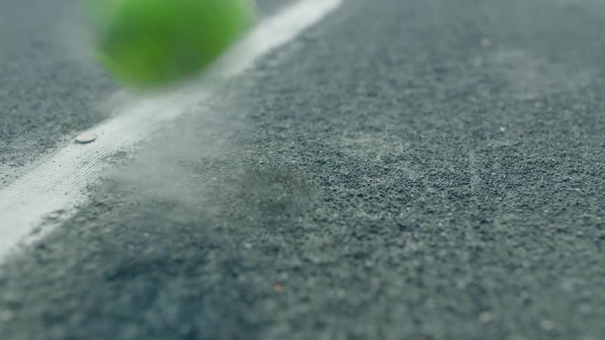 Close up of a tennis ball bouncing near a white line on the court floor
