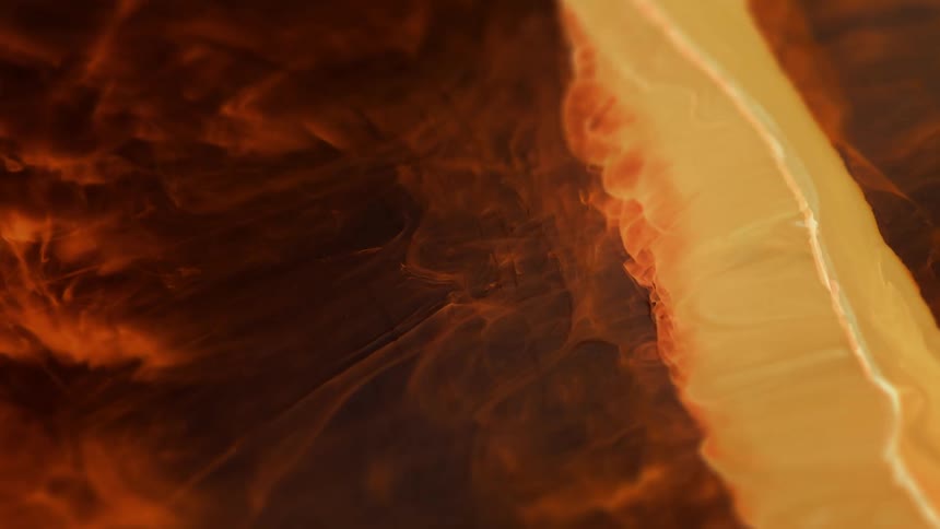 Orange and gold fluid expands while emitting smoke