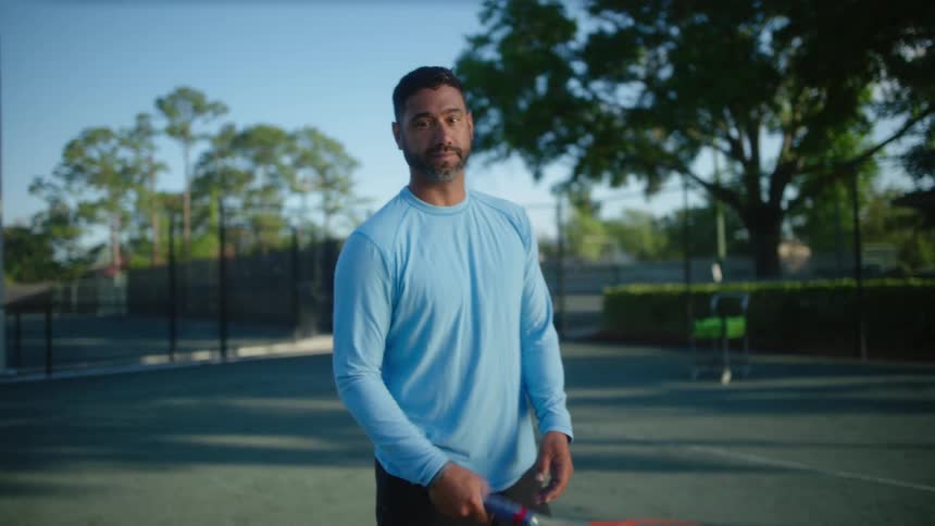 Bearded man on a tennis court spinning his racket