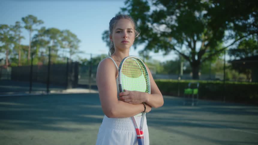 Portrait of a woman on a tennis court holding a racket in her arms