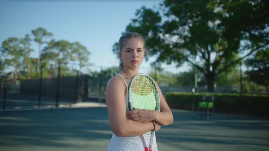 A young tennis player holds a racket while standing on a court