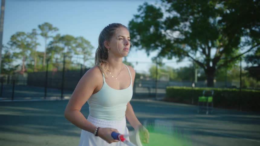Blonde woman swinging her racket while standing on a tennis court