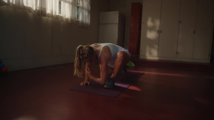 Blonde woman stretching her body during functional exercise indoors