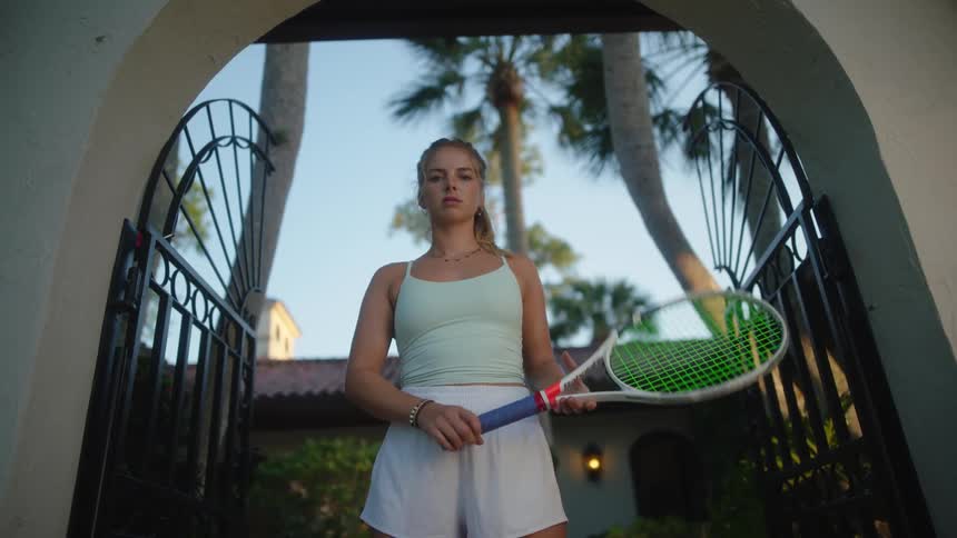 Young woman with serious expression holding a tennis racket