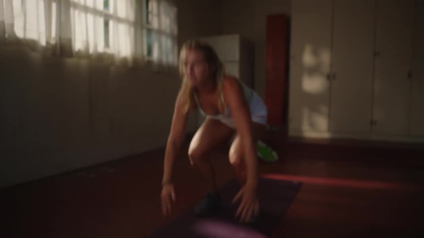 A blonde woman is doing burpees on a red carpet