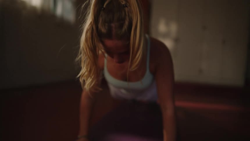 A blonde woman is doing pushups on top of a small red mattress