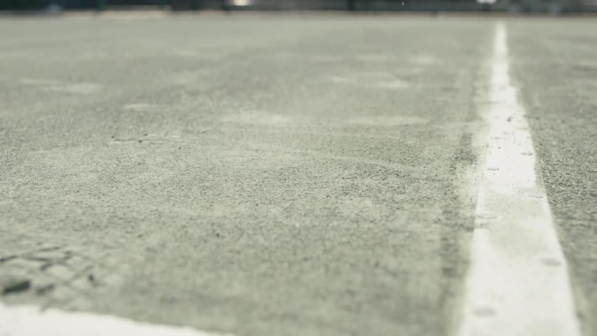 Tennis ball bouncing off tennis court near the line stirs up dust