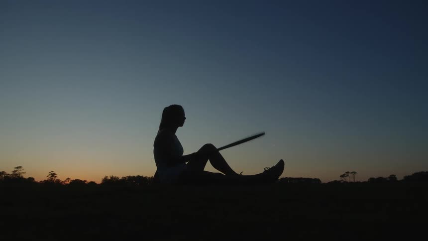 Silhouette of a seated woman holding a tennis racket