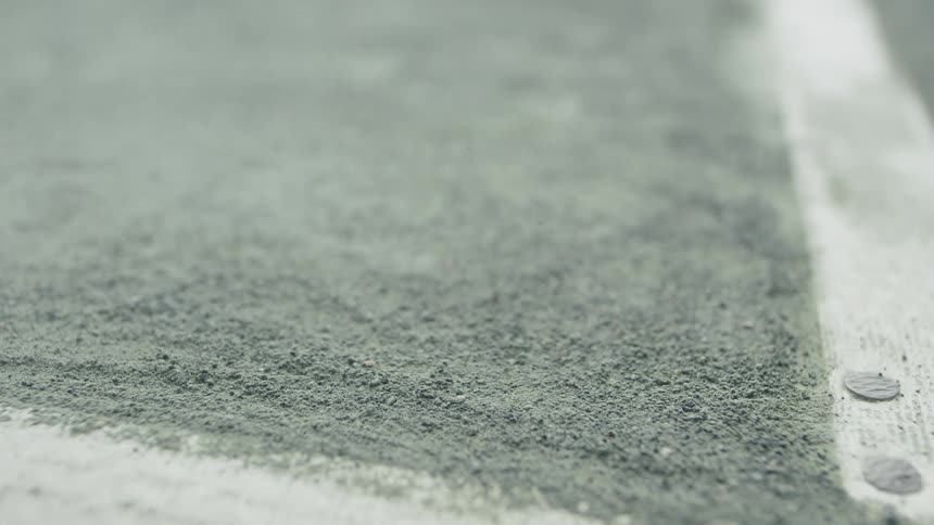 A tennis ball hits clay right next to a court line