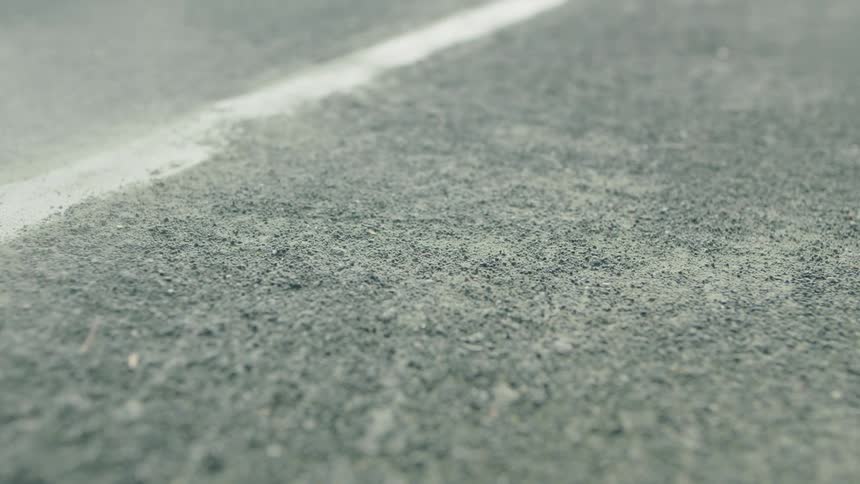 A tennis ball bounces on the floor of a court kicking dust