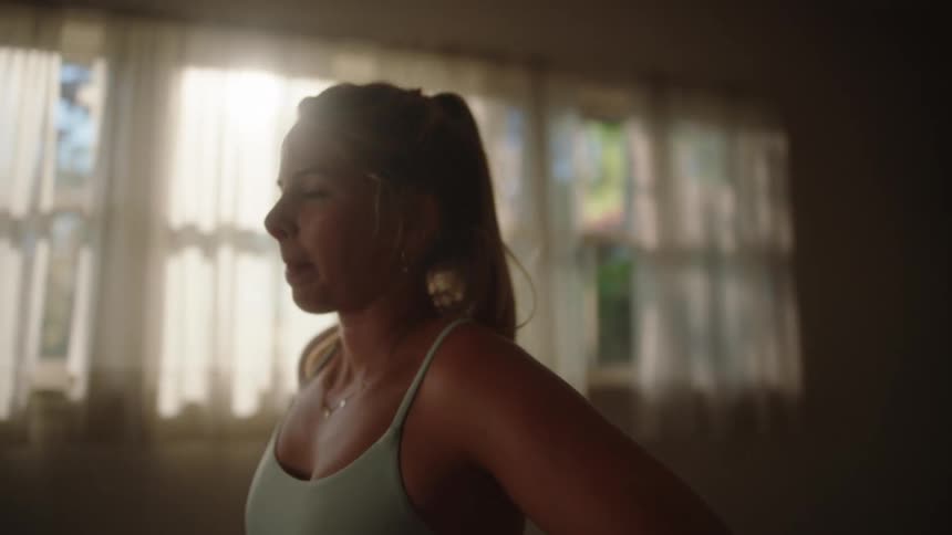 A woman stretches before working out on a dimly lit room at morning