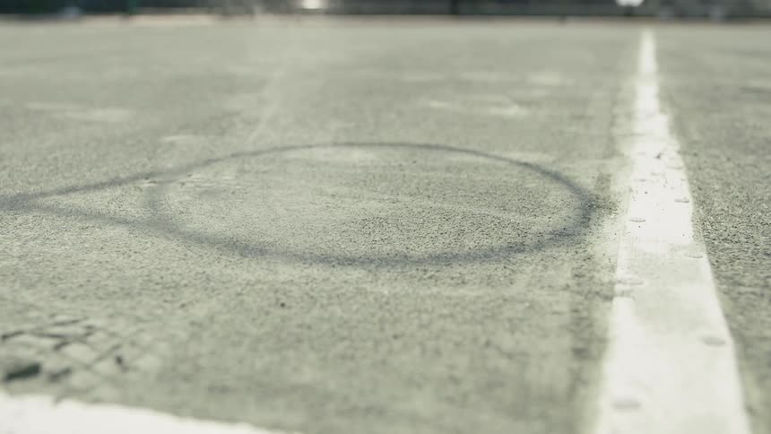 Tennis ball bounces off tennis court near shadow of racket and court line