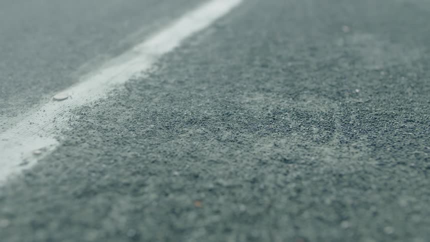 A green tennis ball bounces near a line in the court floor kicking up dust