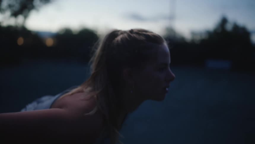 Young blonde woman stretching her body on a court in the late afternoon
