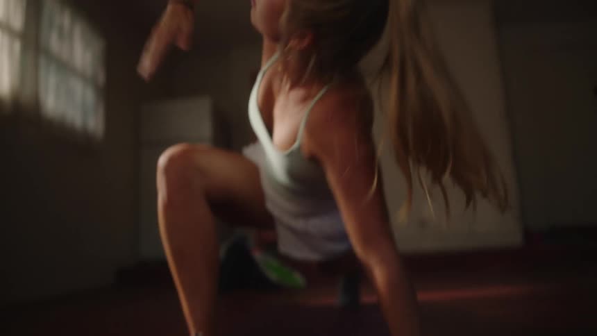A woman stretching on a mat at home reaches one arm up to the ceiling then repeats