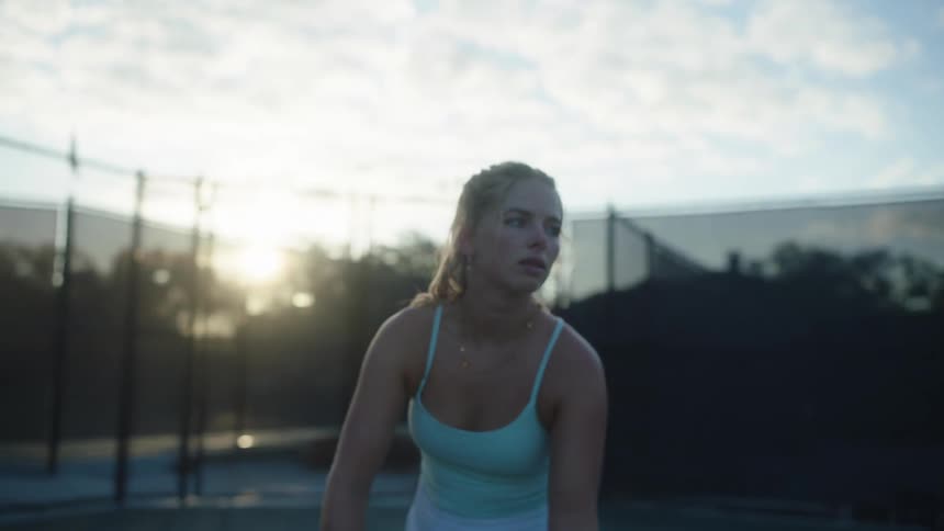 A female tennis player serves a ball in a tennis court at morning practice