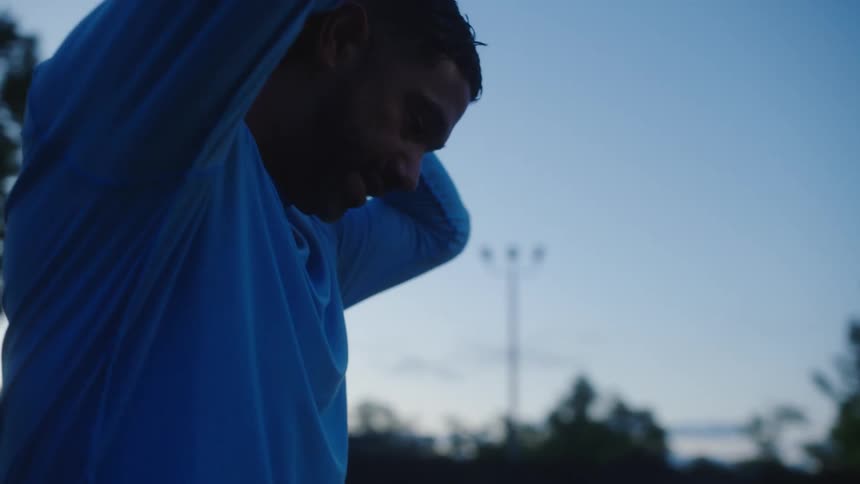 Man stretching his arms behind his head in an open air place
