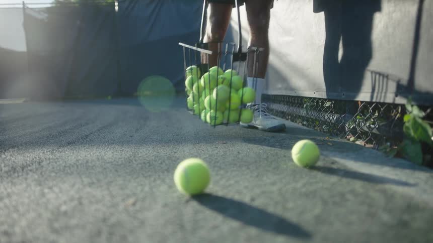 Person with a basket collecting tennis balls