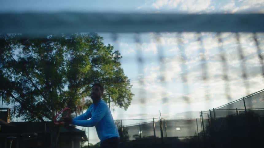 Man with a racket playing tennis on a court