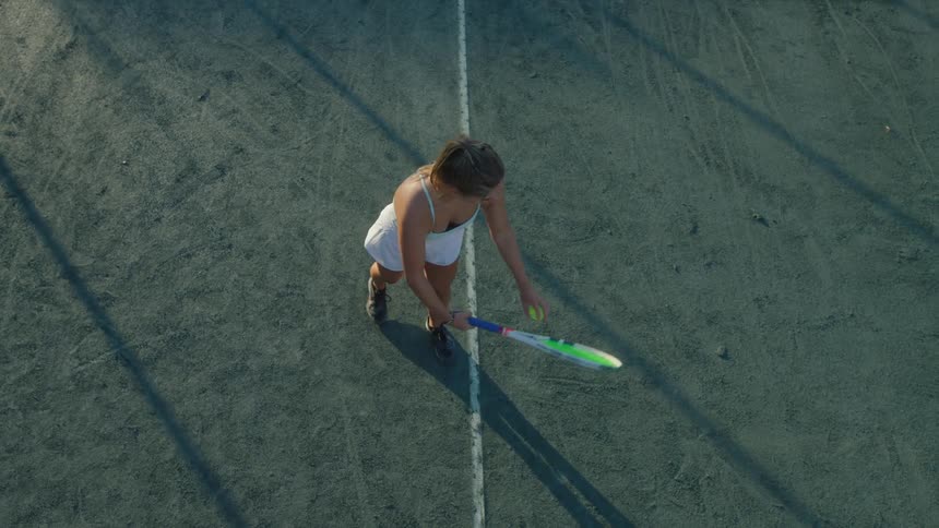 A woman playing tennis serves a ball in the court