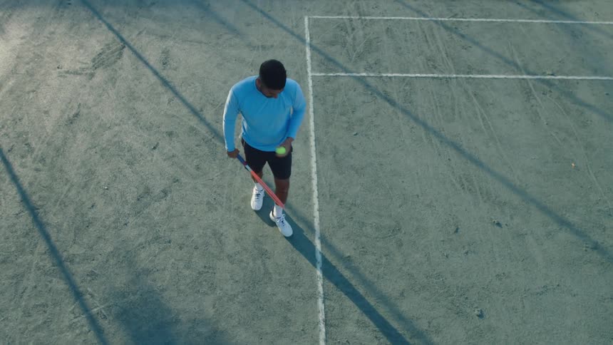 A male tennis player practicing his serve