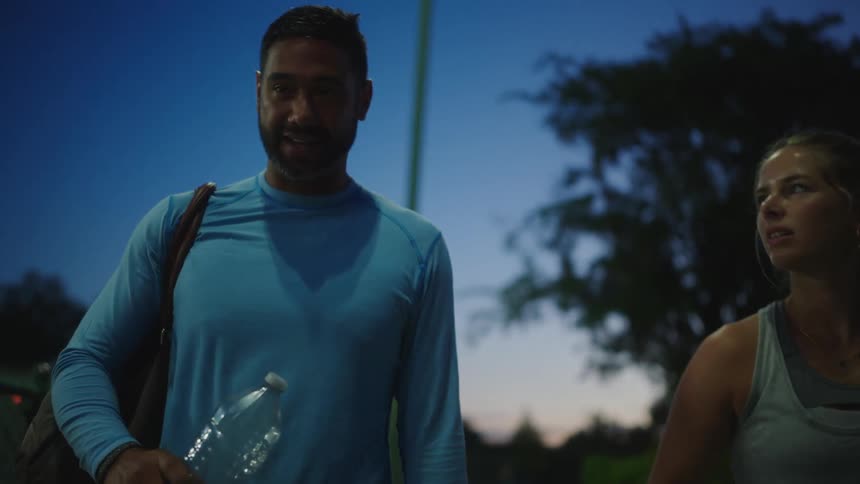 Man and woman with tennis equipment walking side by side