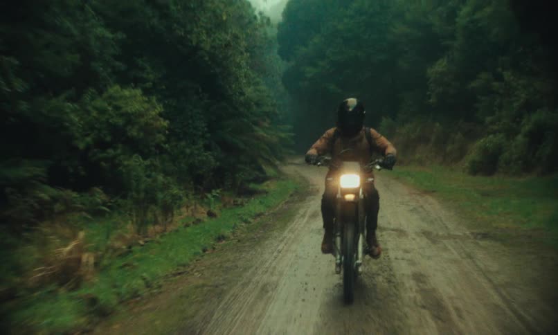 Person riding a motorcycle along a clay path in the middle of nature
