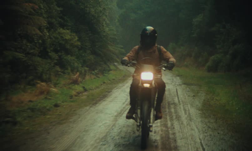 A person riding a motorcycle on a dirt road surrounded by lush vegetation