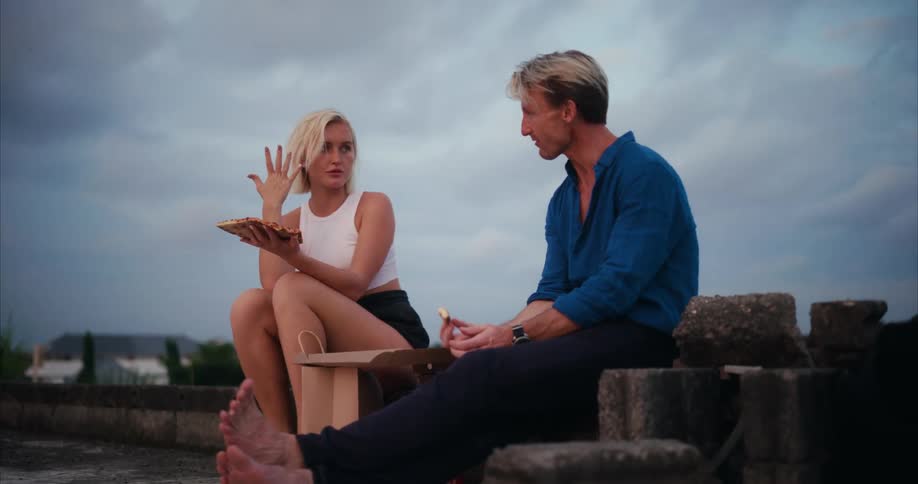 A man and woman are talking and eating outside