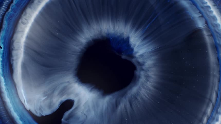 A white and blue liquid expands like an iris against a dark background