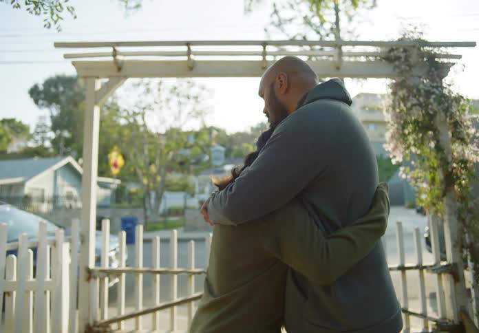 Couple hug in fenced in front yard before approaching gate