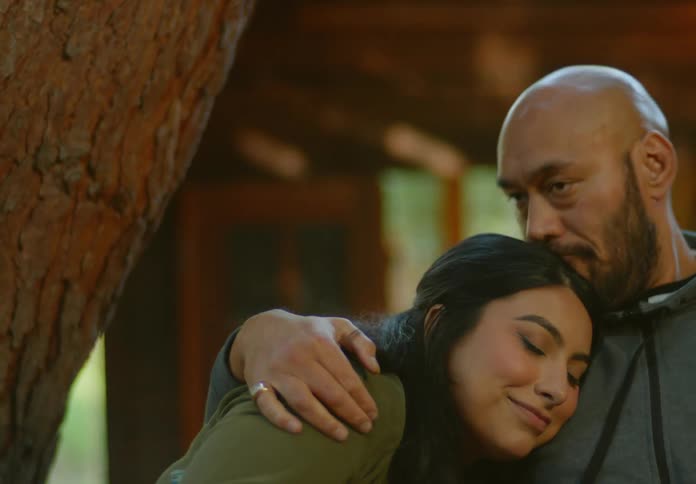 Man and woman sitting outdoors hugging each other