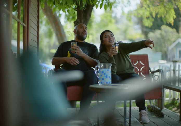 Man and woman sitting with glasses of drink in hand talking in the backyard