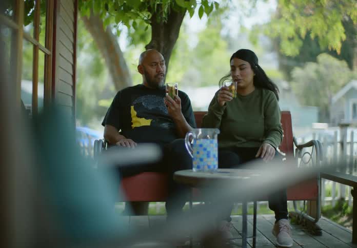Man and woman sitting on a chair toasting and drinking juice