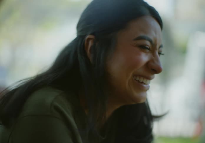 A young middle eastern woman is sitting outside while talking and laughing