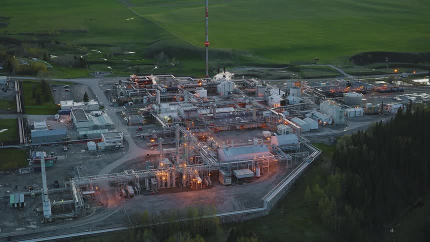An aerial view of a refinery near the forest at night time