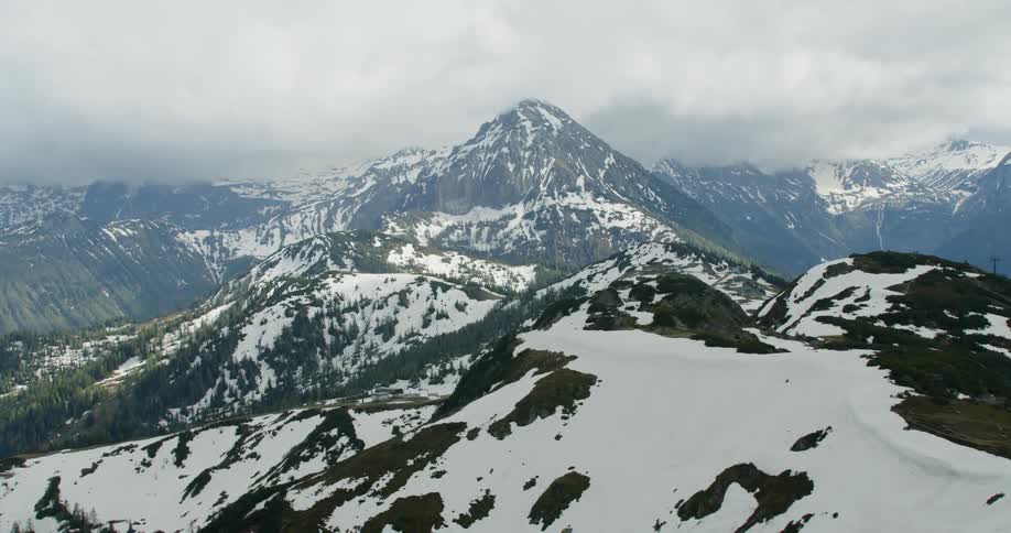 Aerial view of a mountain range with patches if snow on its slopes