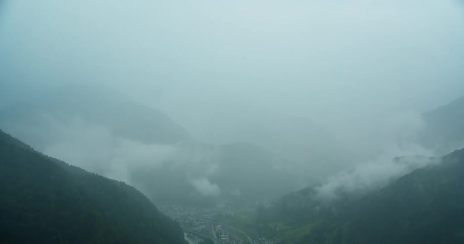 Aerial scenery of a village surrounded by mountains on a foggy day