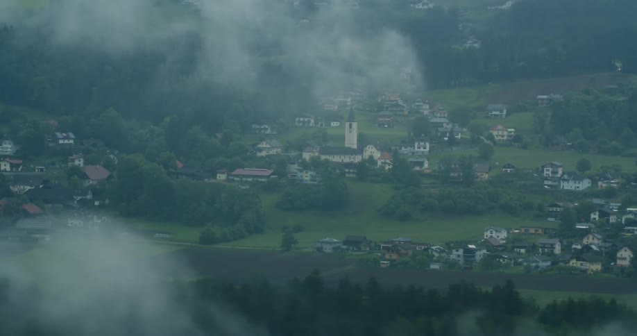 Aerial panorama of a community built on hills surrounded by greenish mountains