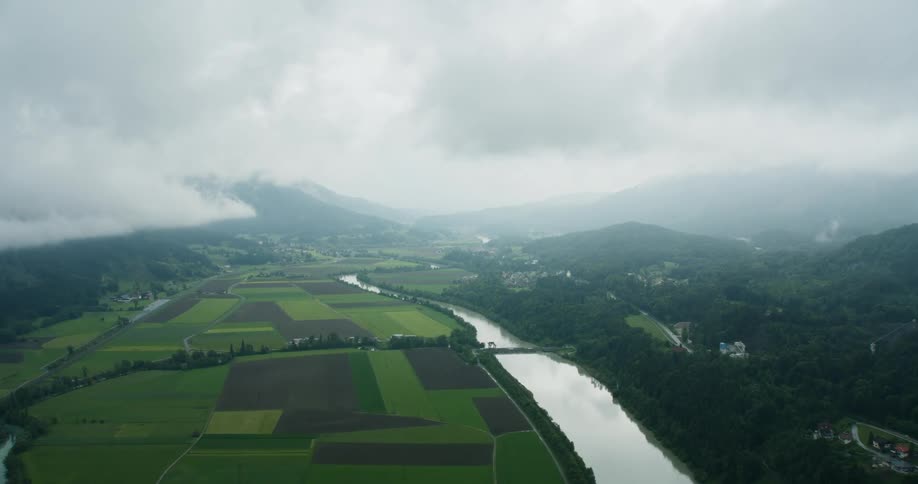 Aerial panorama of agricultural fields by a river on a cloudy day
