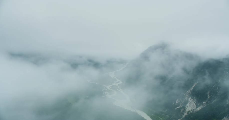 A valley with a river seen from an aerial view with dense fog in front