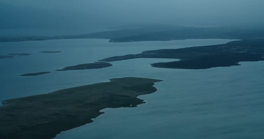 An aerial view of an archipelago with large islands in a bay of water and with a haze on the horizon