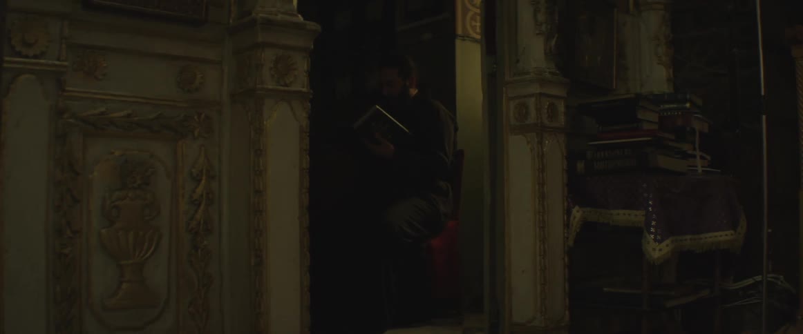 A man sits in a red chair reading